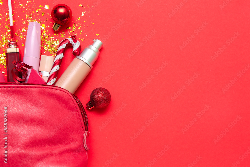 Cosmetic bag with makeup products and Christmas decor on red background