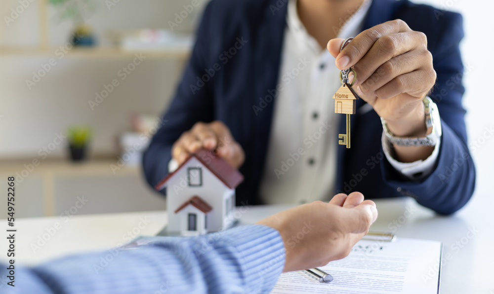 Real estate agent hands over the house keys to a homebuyer after the purchase agreement has been sig