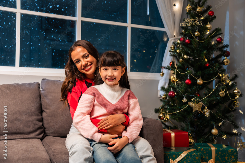 Caucasian young daughter sit on sofa with mother during Christmas time. 