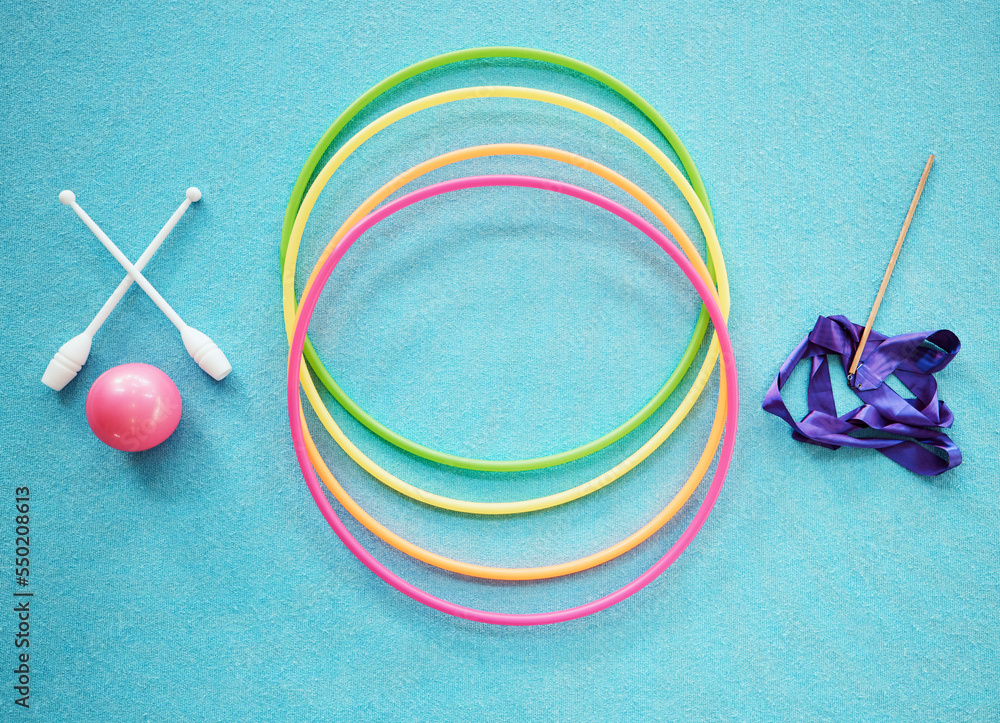 Gymnastics, dance and fitness with a hula hoop, ribbon and bars on an empty blue floor from above fo