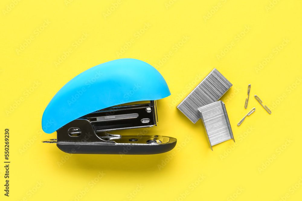 Office stapler with staples on yellow background