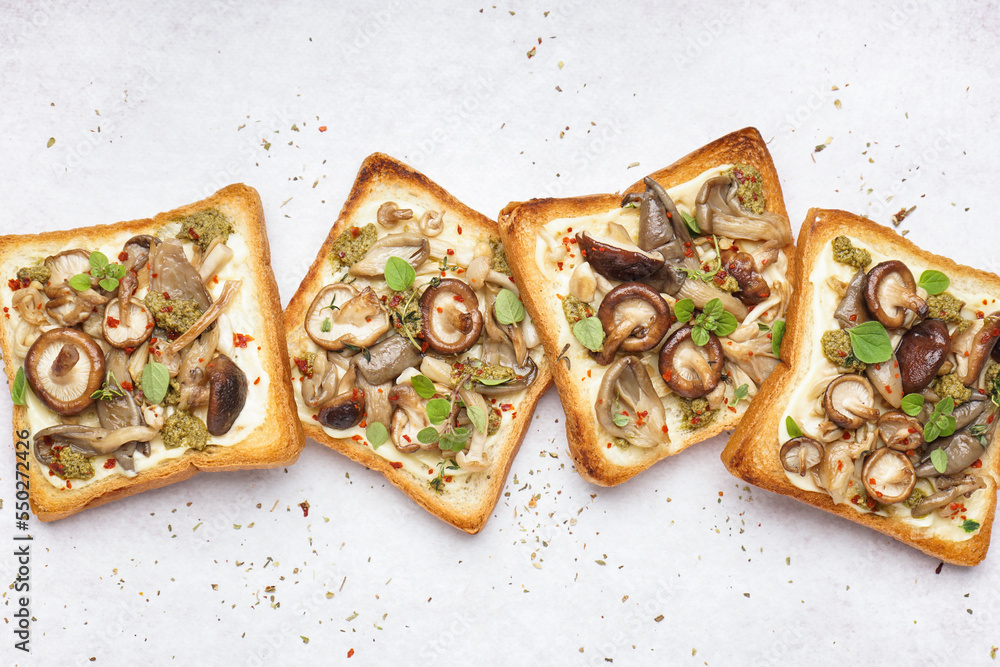 Tasty toasts with cream cheese, mushrooms and pesto sauce on light background