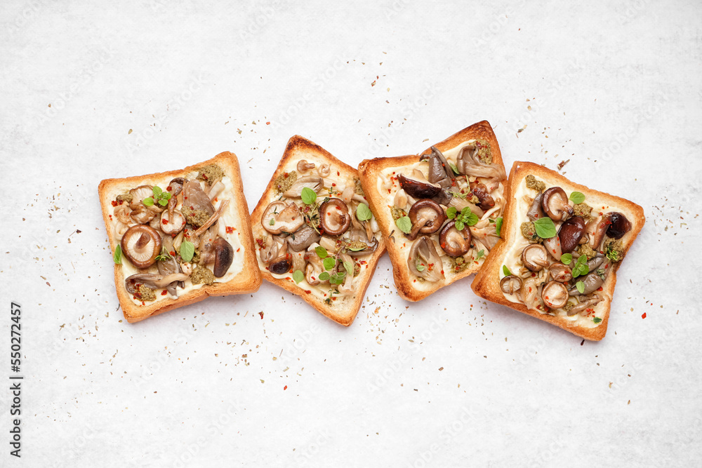 Tasty toasts with cream cheese, mushrooms and pesto sauce on light background