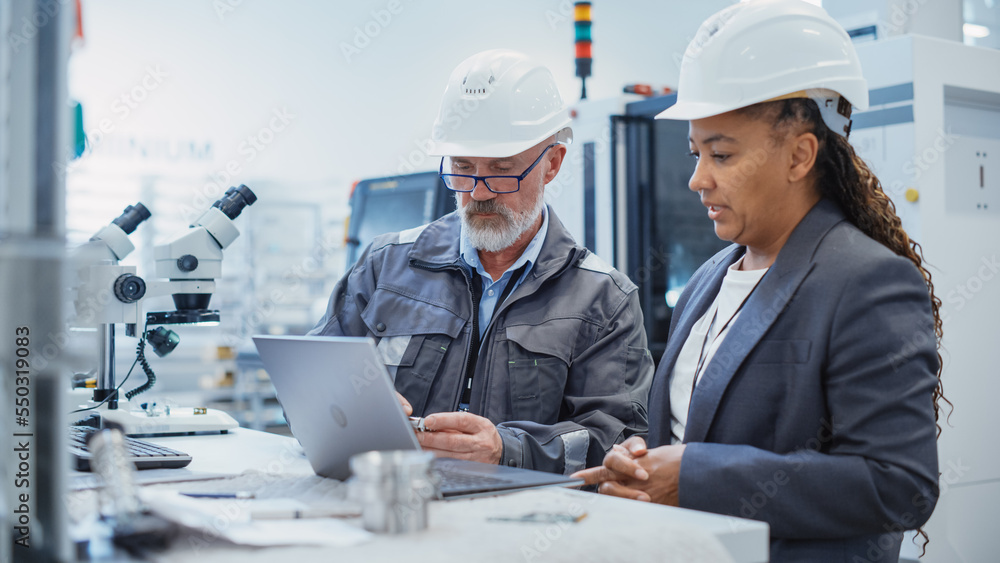 Two Professional Heavy Industry Engineers Wearing Safety Uniform and Hard Hats Discussing Industrial