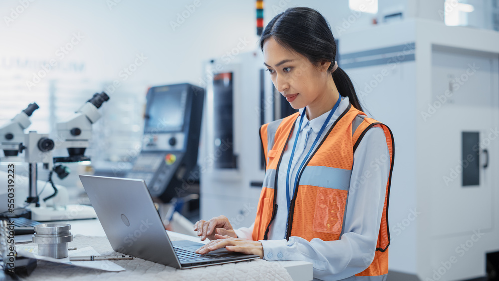 Portrait of an Asian Female Engineer in Orange Safety Vest Working on Laptop Computer at Electronic 