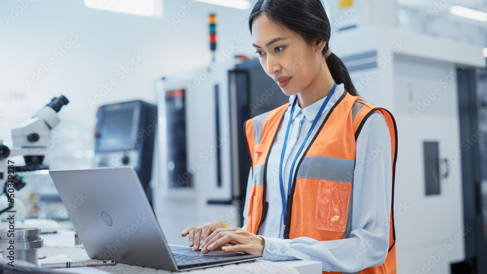 Research and Development Specialist Using Laptop to Operate a Heavy Industry Machine at a Factory. A