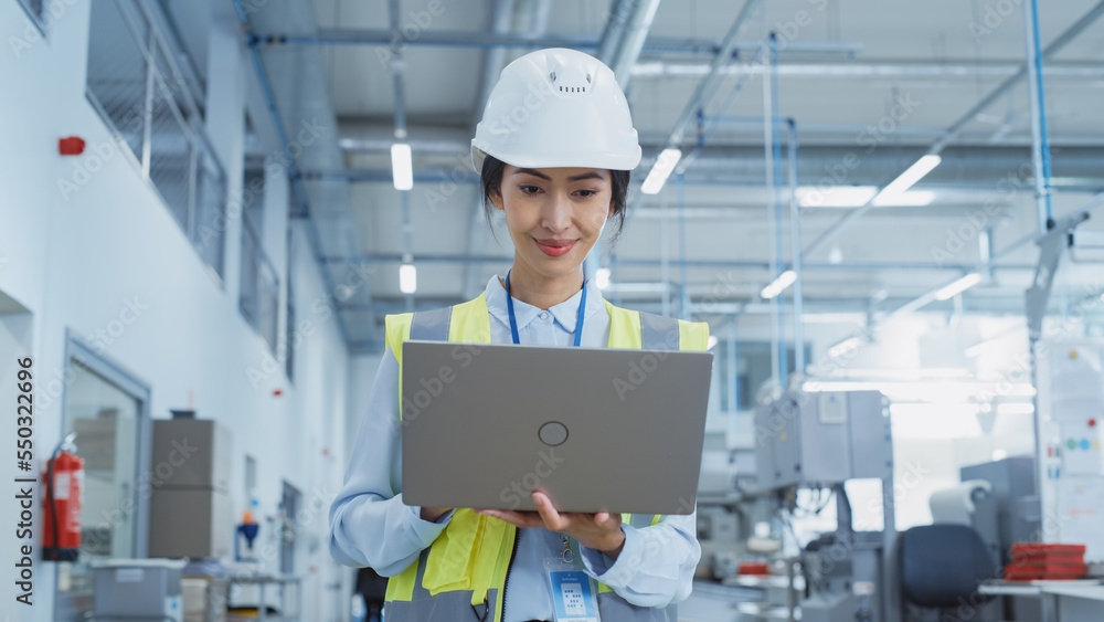 A Happy and Smiling Asian Female Engineer in White Hard Hat Standing with Laptop Computer at Electro