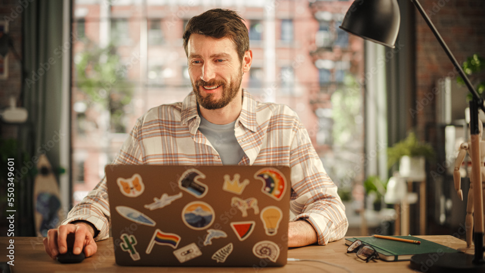 Creative Bearded Man Working on Laptop Computer while Sitting at a Table in Stylish Cozy Loft Living