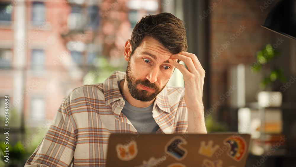 Creative Bearded Man Working on Laptop Computer while Sitting at a Table in Stylish Cozy Loft Living