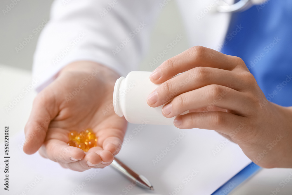 Female doctor with vitamins sitting at table in clinic, closeup