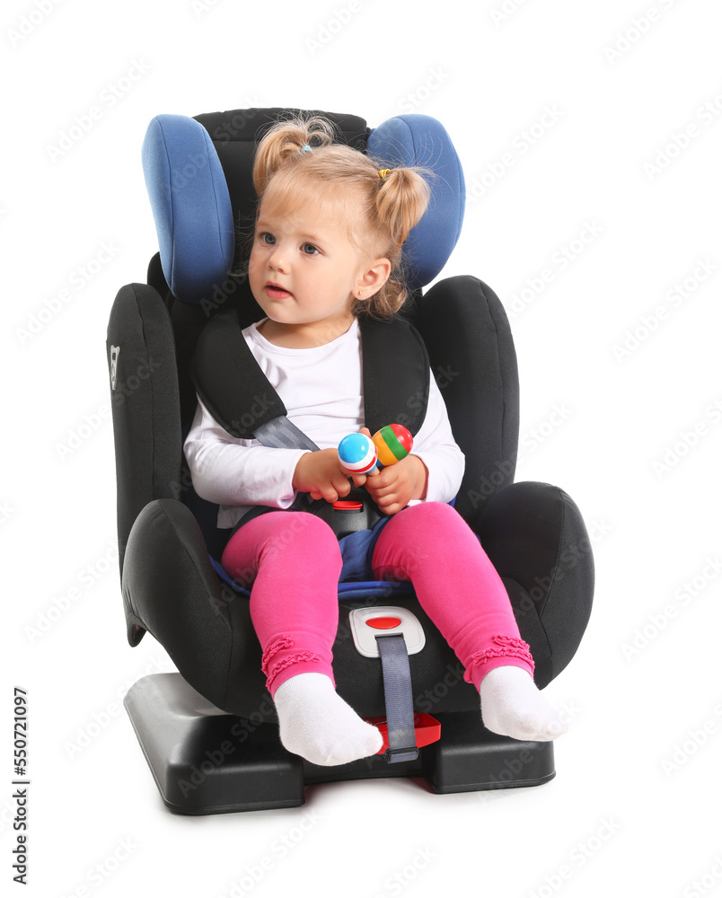 Adorable little girl with maracas buckled in car safety seat on white background