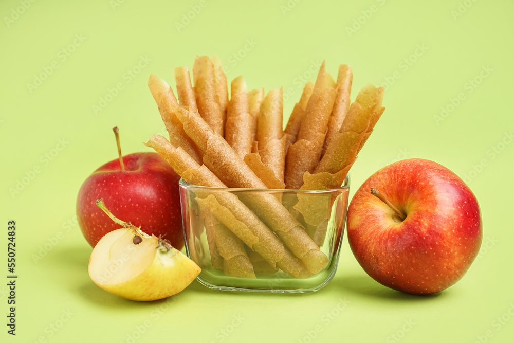 Glass bowl with tasty apple pastilles on green background