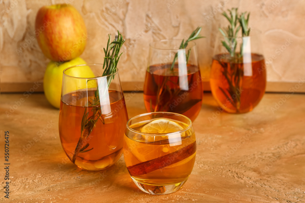 Glasses of fresh apple juice with rosemary on color table