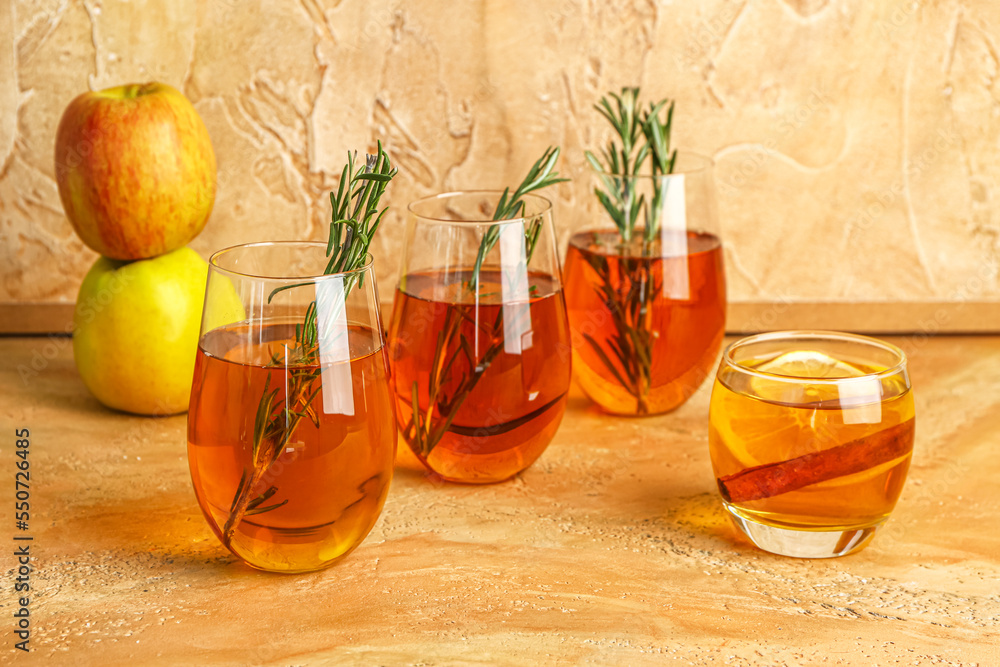 Glasses of fresh apple juice with rosemary on color table