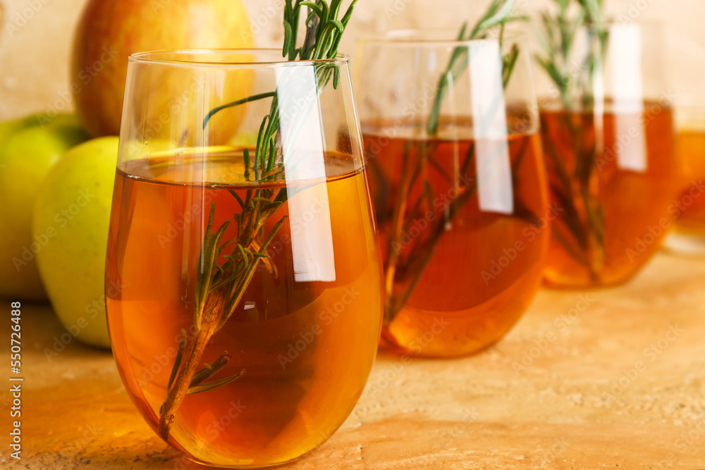 Glasses of fresh apple juice with rosemary on color table, closeup