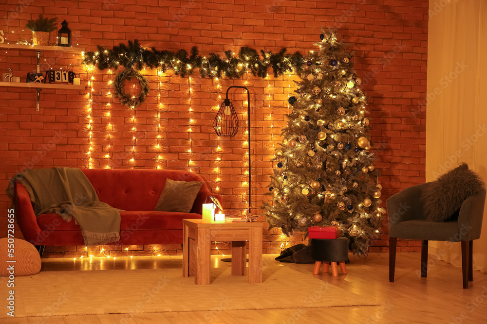 Interior of living room with Christmas tree, sofa and glowing lights at night