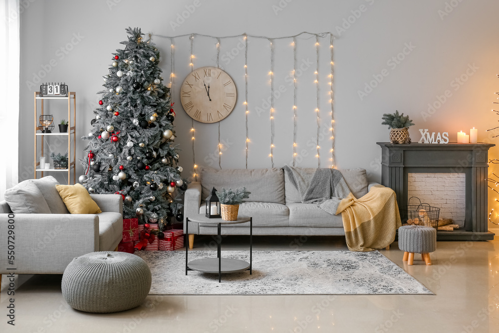 Interior of living room with glowing Christmas tree, sofas and clock