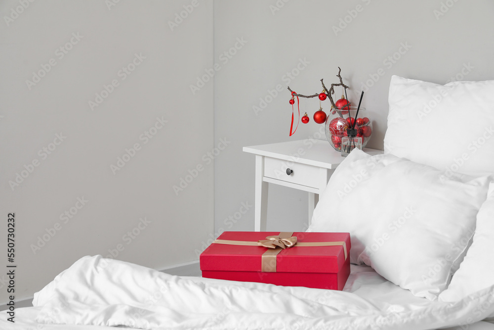 Vase with tree branches, Christmas balls and reed diffuser on table in bedroom