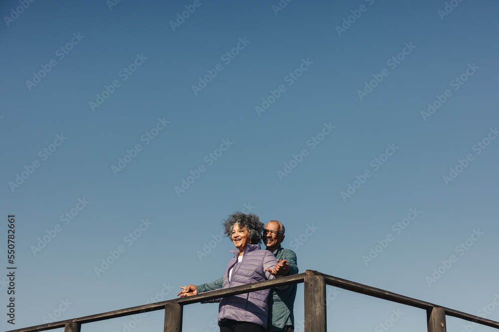 Happy elderly couple having fun on a wooden foot bridge