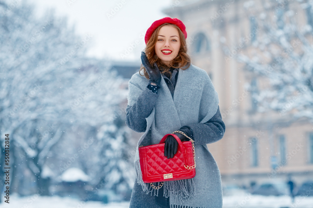 Happy smiling woman enjoying winter holidays, posing in snow covered street of European city. Model 