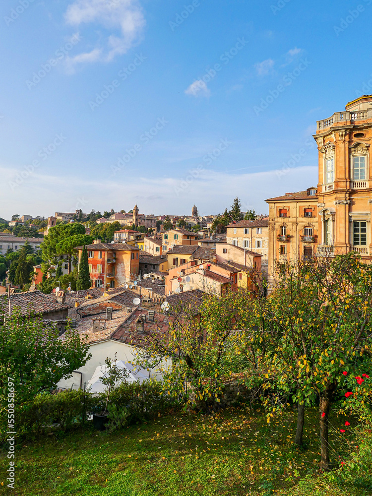 A city view from above, the mountains and the roofs of the houses can be seen. Also there is sunset,