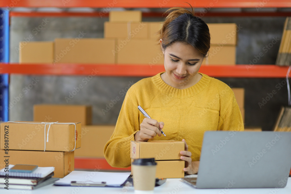 Woman who start up small business works in a warehouse. Start-up entrepreneur is writing a note on a