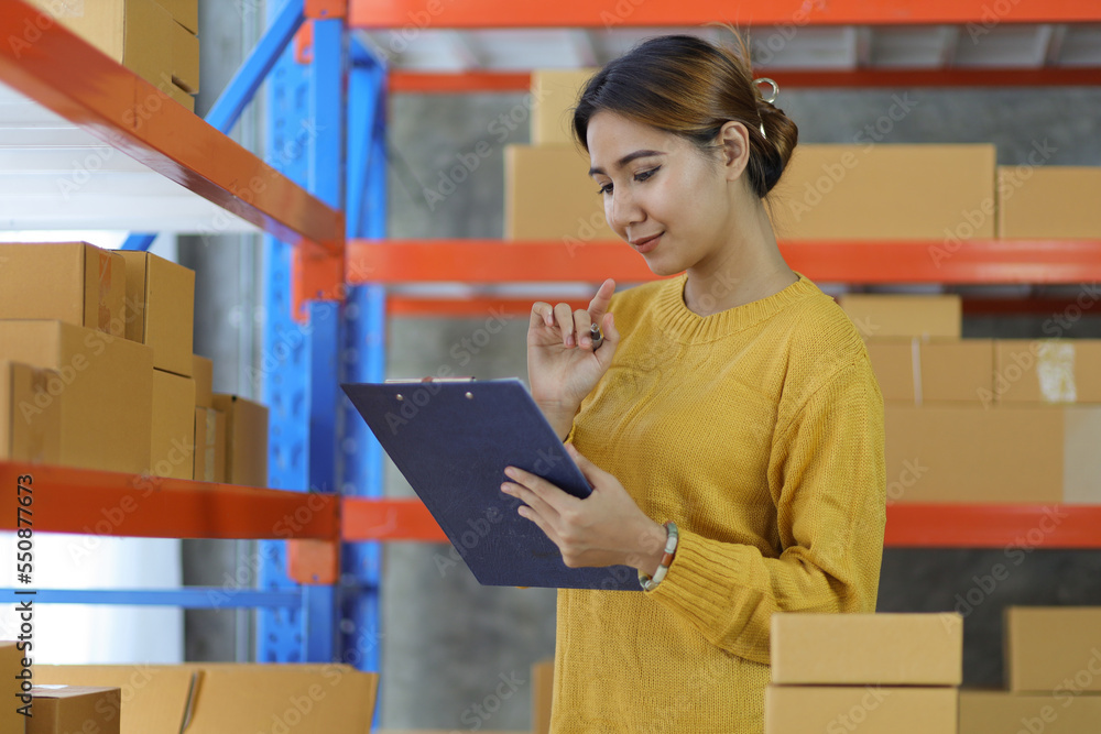 Woman who start up small business works in a warehouse. Start-up entrepreneur is writing a note on a