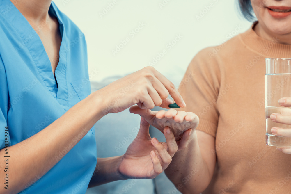 Contented senior woman taking medicines while her caregiver advising her medication. Medication for 