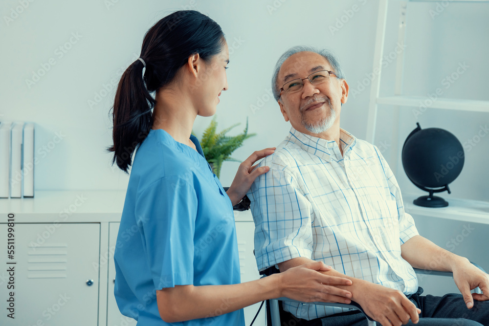 Happy positive asian nurse giving support and touching contented senior man with love. Nursing home 