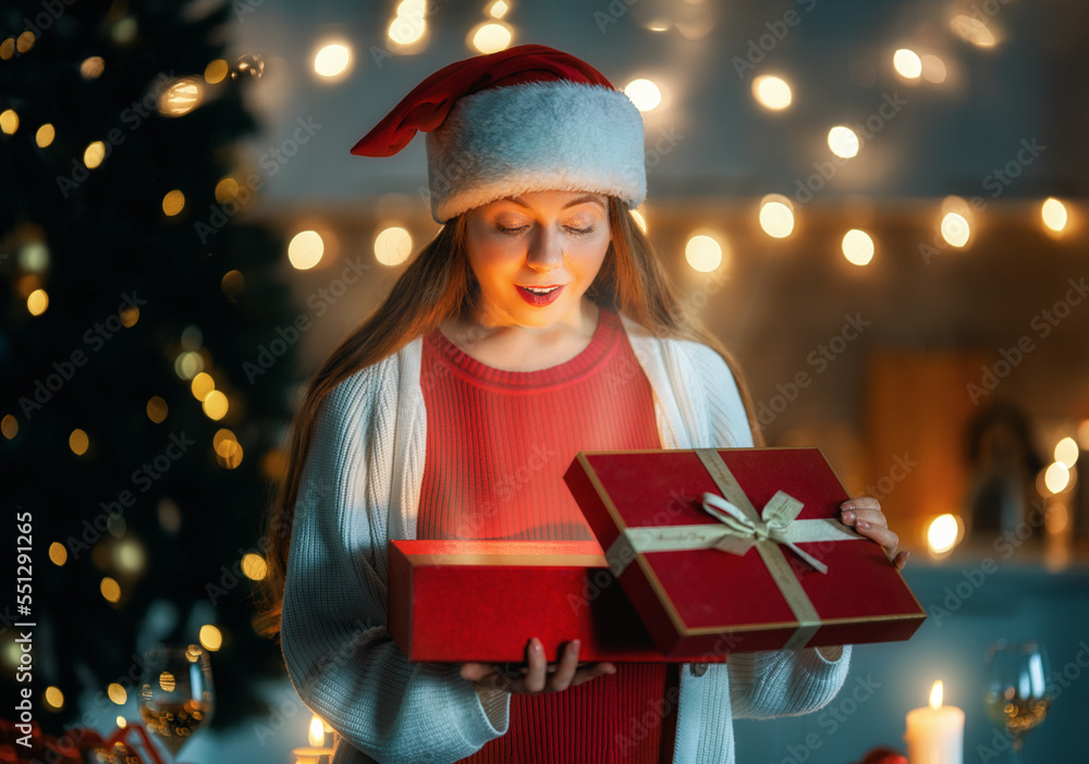 woman with present near Christmas tree indoors