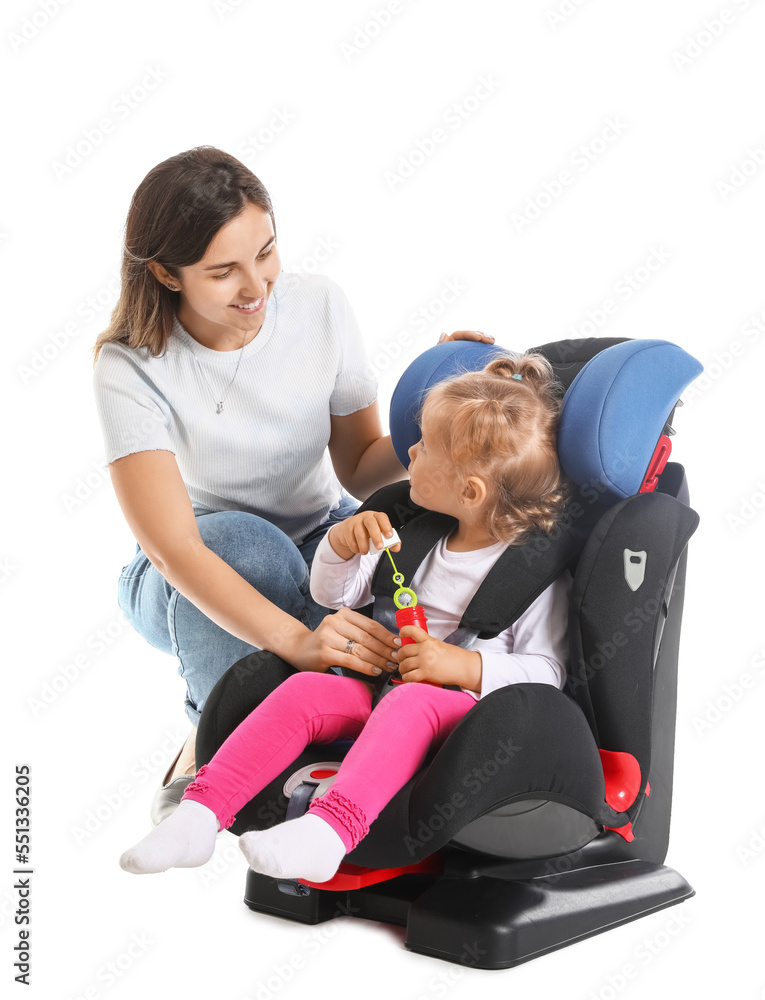 Mother and her little daughter buckled in car safety seat on white background