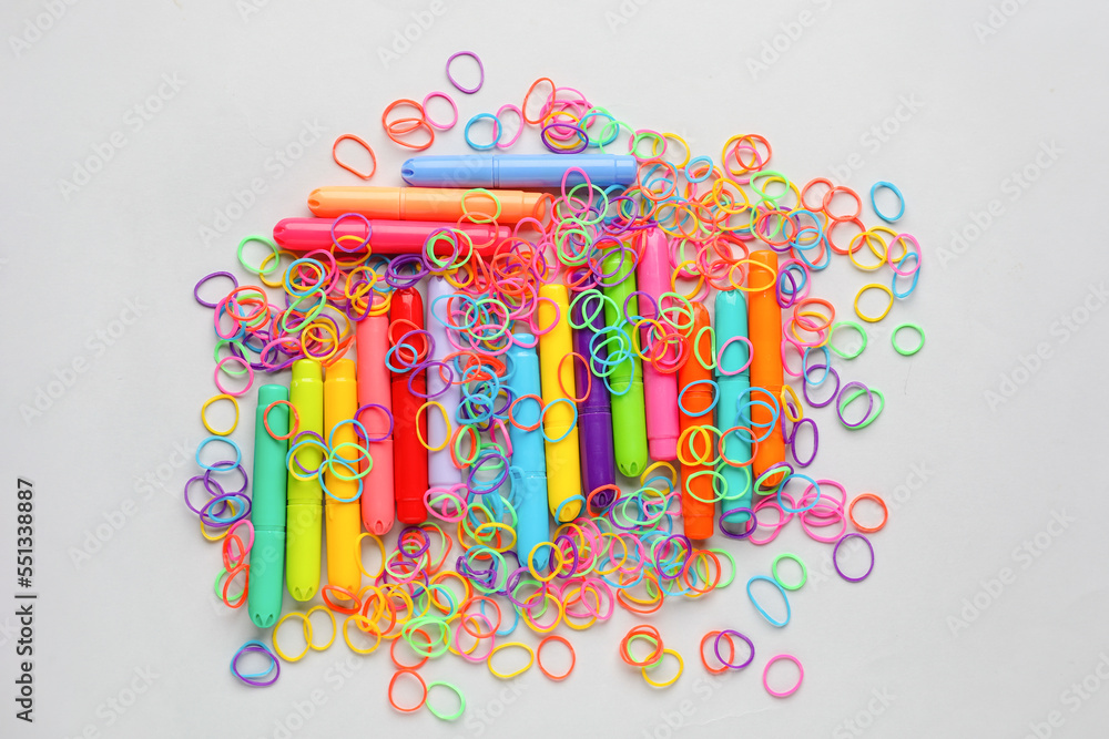 Colorful rubber bands and markers on white background