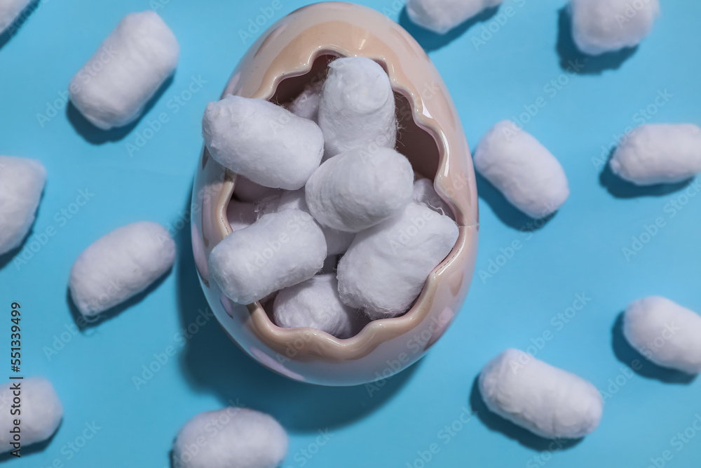 Bowl of cotton balls on blue background