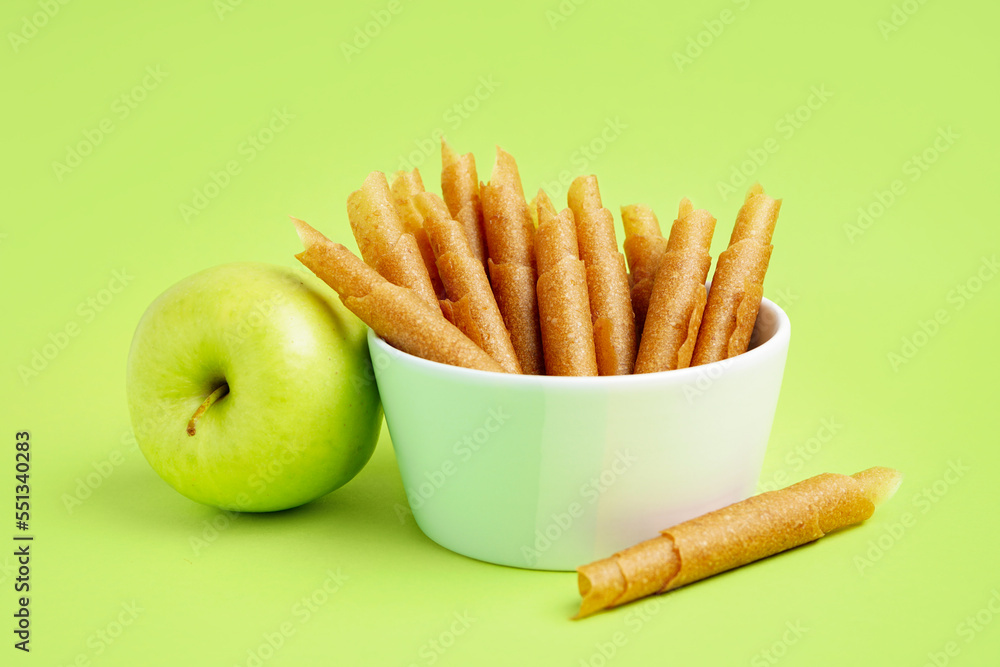 Bowl of tasty apple pastilles on green background