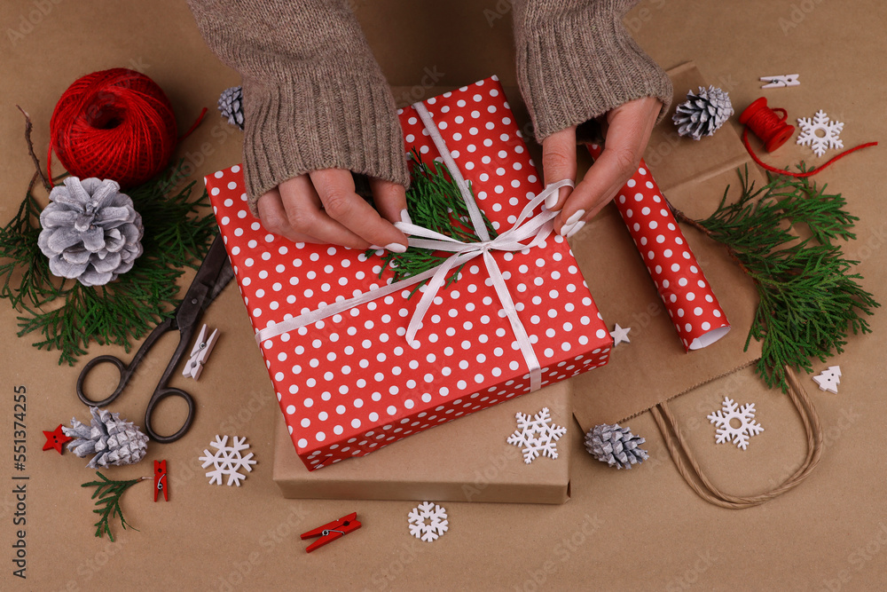 Woman packing Christmas gifts with red paper