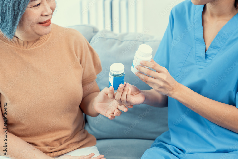 Caregiver advising contented senior woman on medication in the living room. Medication for seniors, 