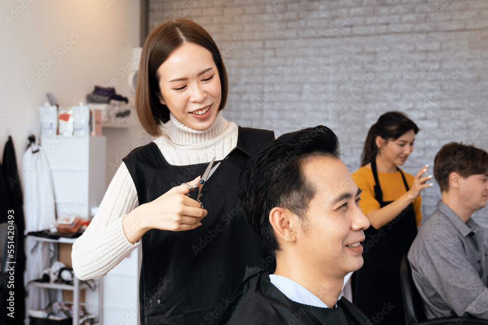 Asian female hairdresser making haircut for two male customer with male hairstyle in qualified barbe