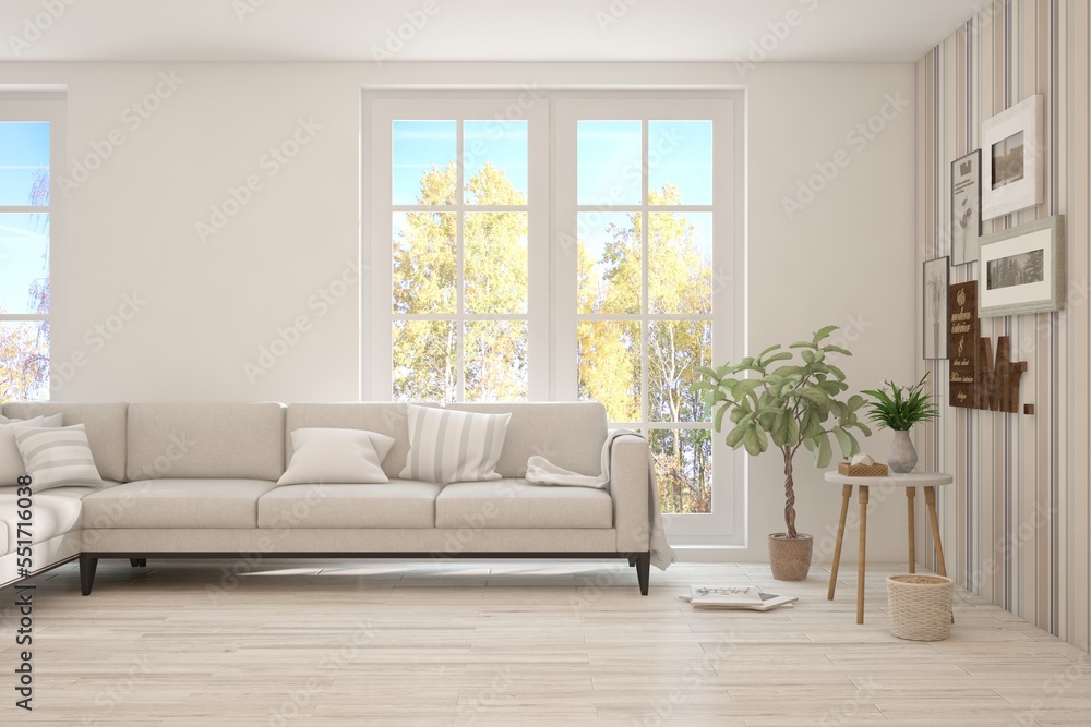 Stylish room in white color with sofa and autumn landscape in window. Scandinavian interior design. 