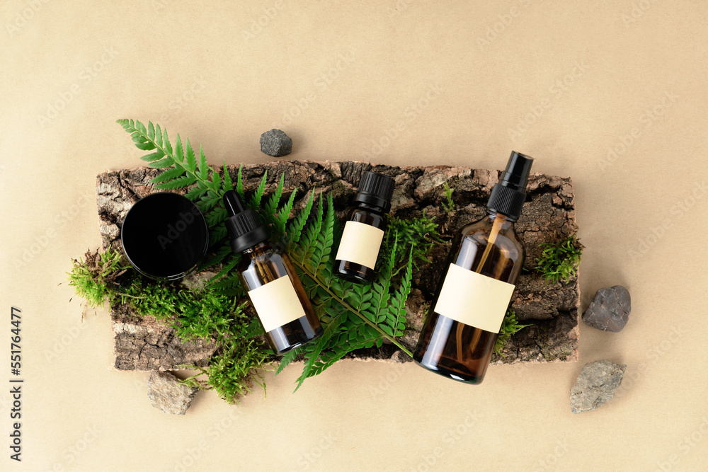 Unlabelled cosmetic bottles on natural beige background, natural moss over branches, bark. Skin care