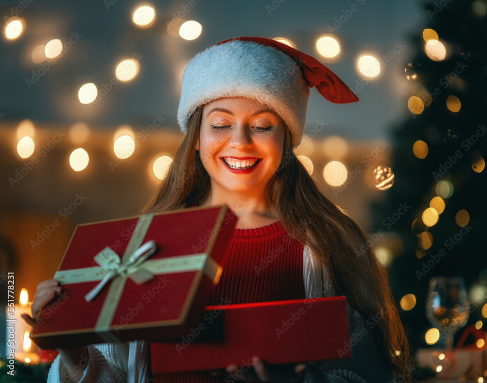 woman with present near Christmas tree indoors