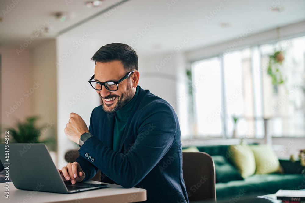 Smiling businessman working over the laptop at the home office.