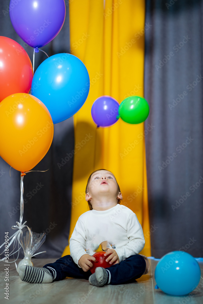 Happy baby boy with colorful balloons. A boy is having fun with a bunch of balloons