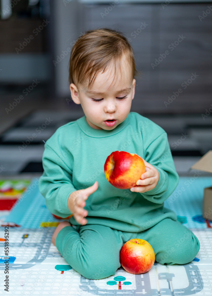 Cute baby boy eating apple at home. Healthy child nutrition