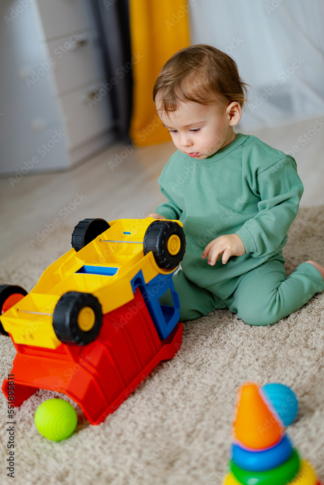 Cute cheerful baby playing with colorful toy at home. Baby boy playing with educational toy.