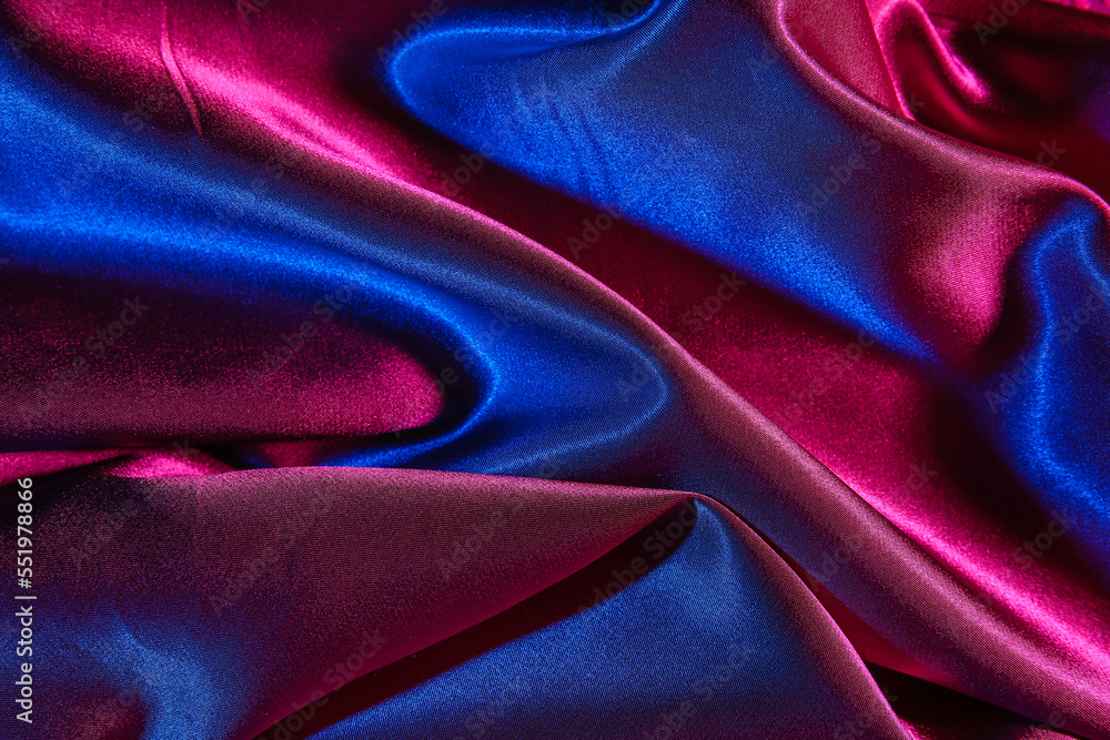 Crumpled silky fabric in neon light as background