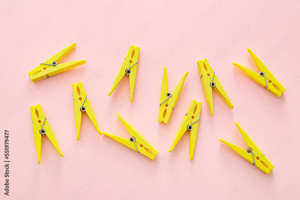 Many yellow clothespins on pink background