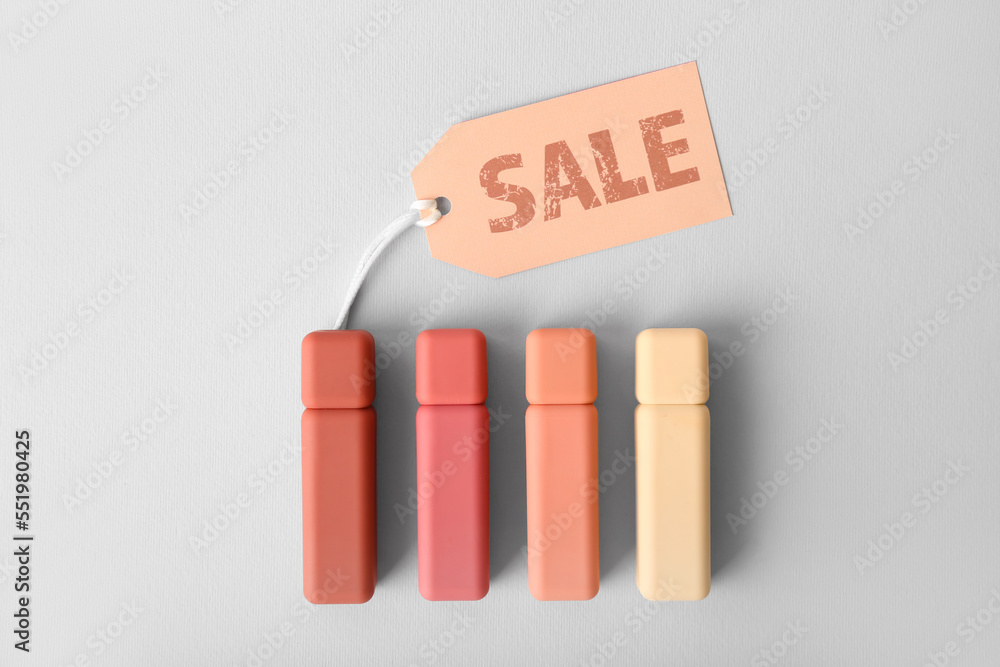 Lipsticks with sale tag on light background