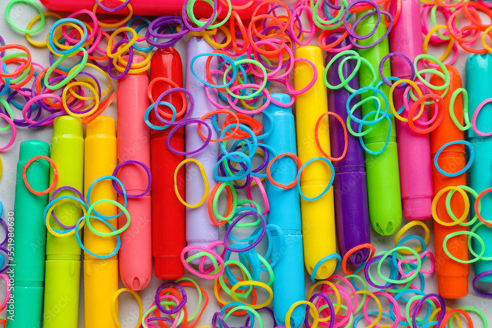 Colorful rubber bands and markers on white background, closeup