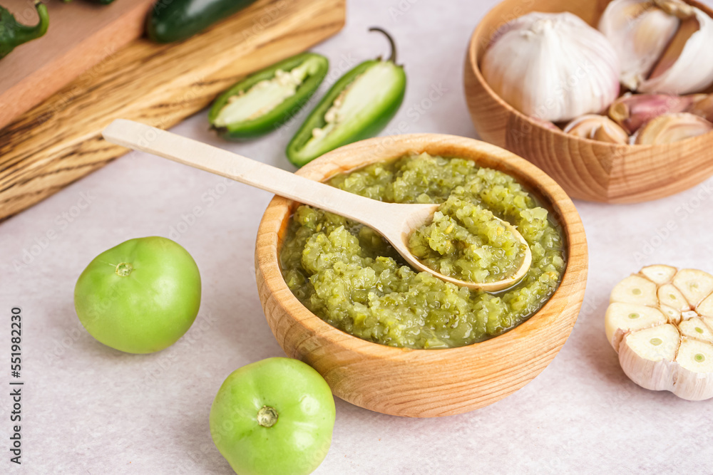 Wooden bowl of tasty green salsa sauce on light table