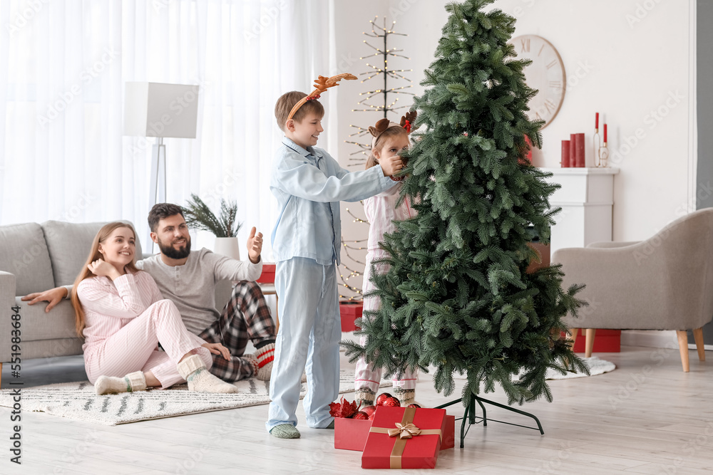 Happy little children decorating Christmas tree at home